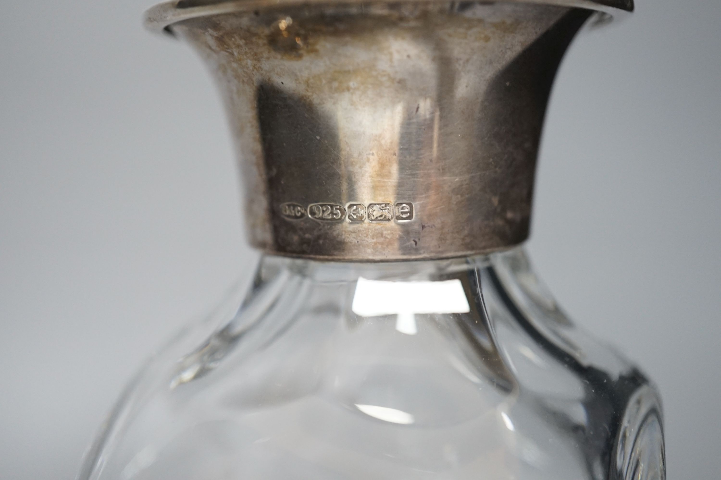 A Victorian circular heavy glass inkwell with hinged silver lid, engraved crest (London 1892) and a silver mounted decanter, 26.5cm